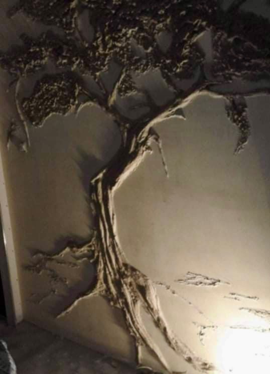 Dekoracyjna ściana z trójwymiarowym wzorem drzewa, wykonana z beżowej gładzi strukturalnej. Efektowna ozdoba wnętrza.