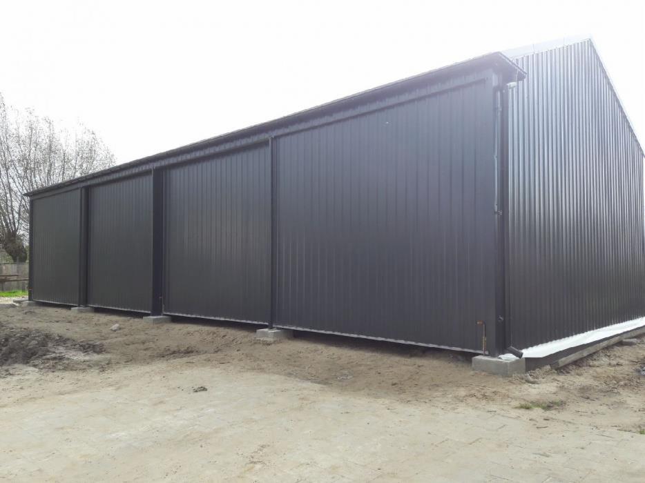 Gotowa hala z szarej blachy trapezowej z przesuwnymi drzwiami, widok z zewnątrz na betonowych fundamentach.