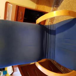 Sanpa Sp. z o.o. - Niebieskie krzesło biurowe z drewnianymi podłokietnikami widziane z góry, na siedzisku widoczne lekkie odbarwienia.