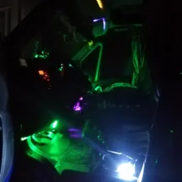 Wnętrze kabiny busa z podświetleniem LED w kolorach zielonym i fioletowym, widoczny fotel kierowcy, deska rozdzielcza i oświetlenie pod nogami.