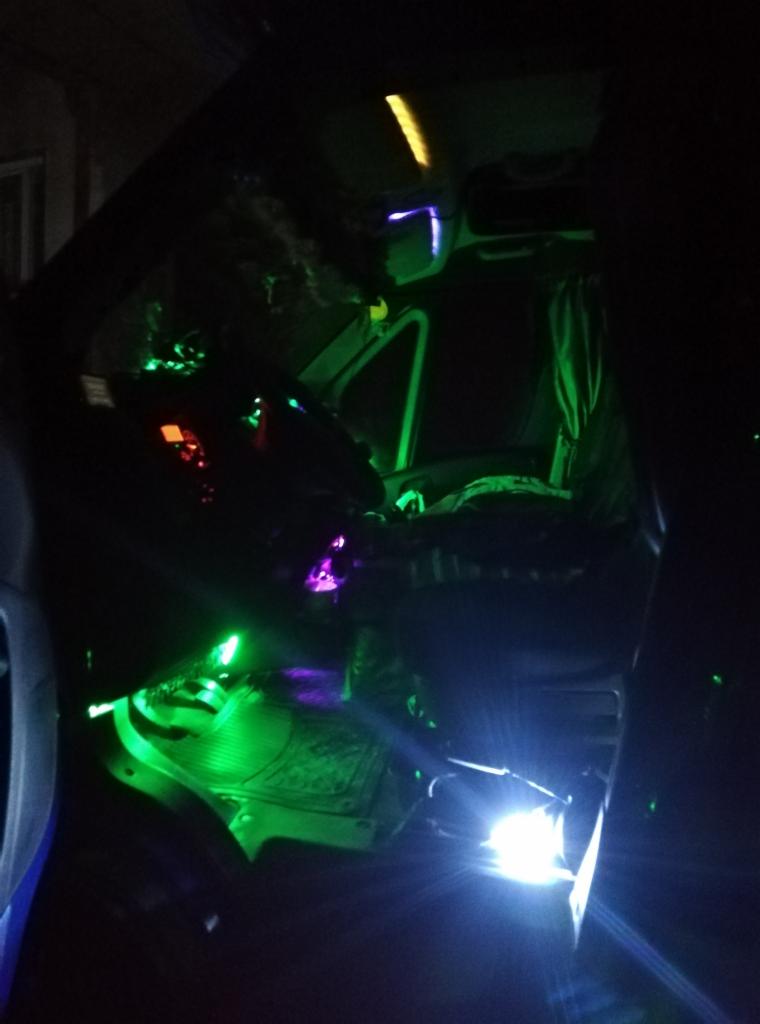 Wnętrze kabiny busa z podświetleniem LED w kolorach zielonym i fioletowym, widoczny fotel kierowcy, deska rozdzielcza i oświetlenie pod nogami.