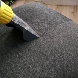 Czyszczenie tapicerki krzesła szarą dyszą odkurzacza piorącego, widoczna różnica w odcieniu po prawej stronie.