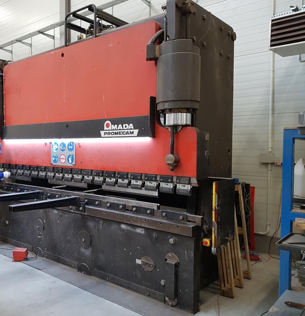 Czerwono-czarna prasa krawędziowa AMADA PROMECAM w hali produkcyjnej, z widocznymi elementami konstrukcji stalowej w obszarze roboczym.