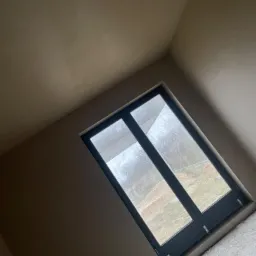 Świeżo otynkowane wnętrze z zamontowanym oknem, widoczne ślady po szpachlowaniu i przygotowaniu do malowania.