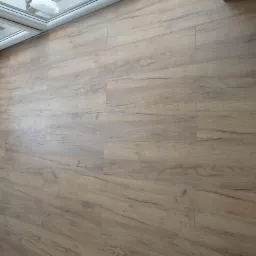 Ułożona podłoga z paneli imitujących drewno, widok z góry, fragment okna dachowego w lewym górnym rogu.