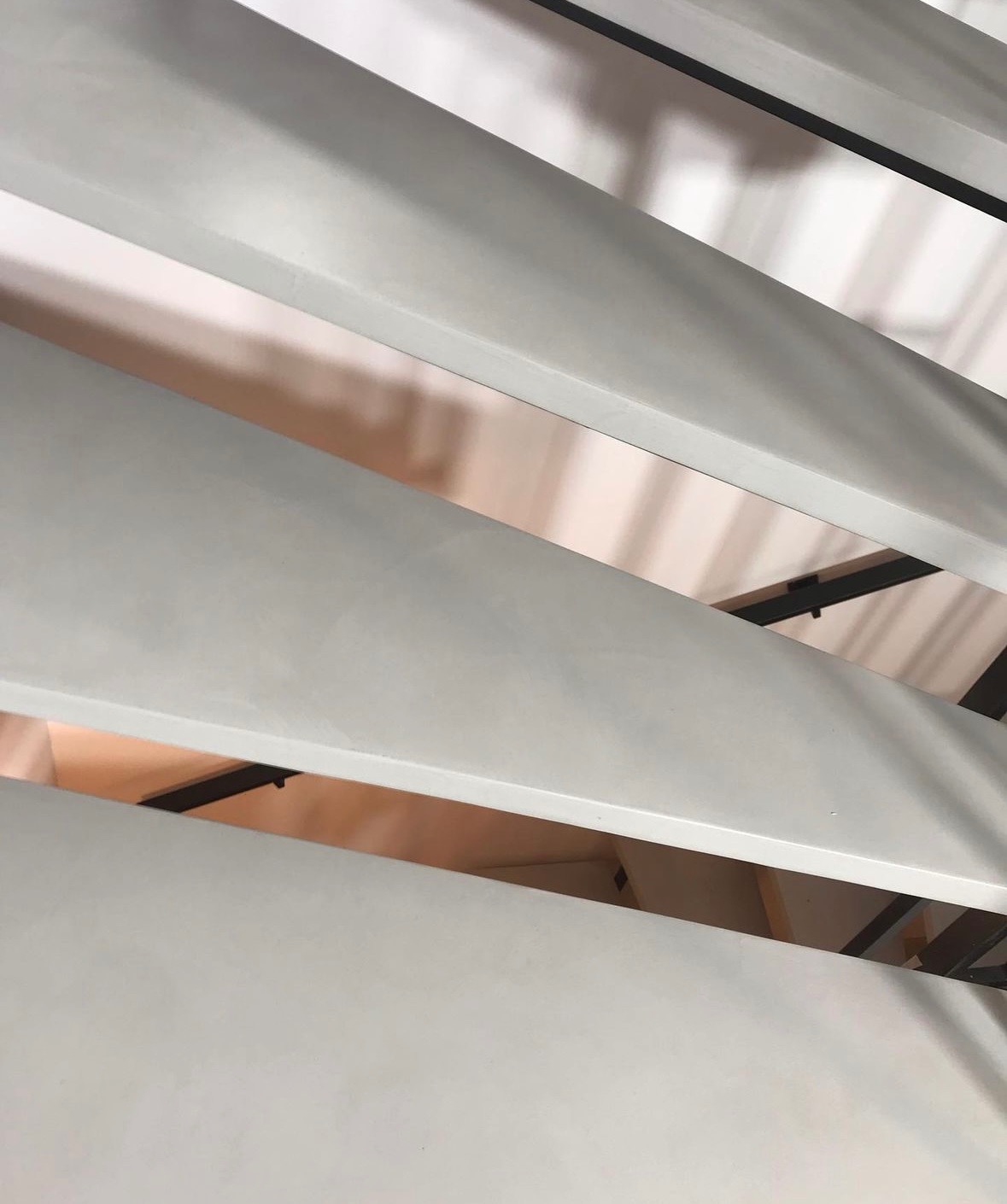 Szare, poziome panele z czarnymi elementami konstrukcyjnymi, ułożone pod kątem, widok z dołu.