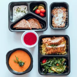 Zestaw pięciu pudełek z różnorodnymi daniami dietetycznymi, w tym zupa krem z zielonym akcentem, łosoś z kaszą, sałatka warzywna, pieczywo razowe z twarożkiem i warzywami oraz deser owsiany...