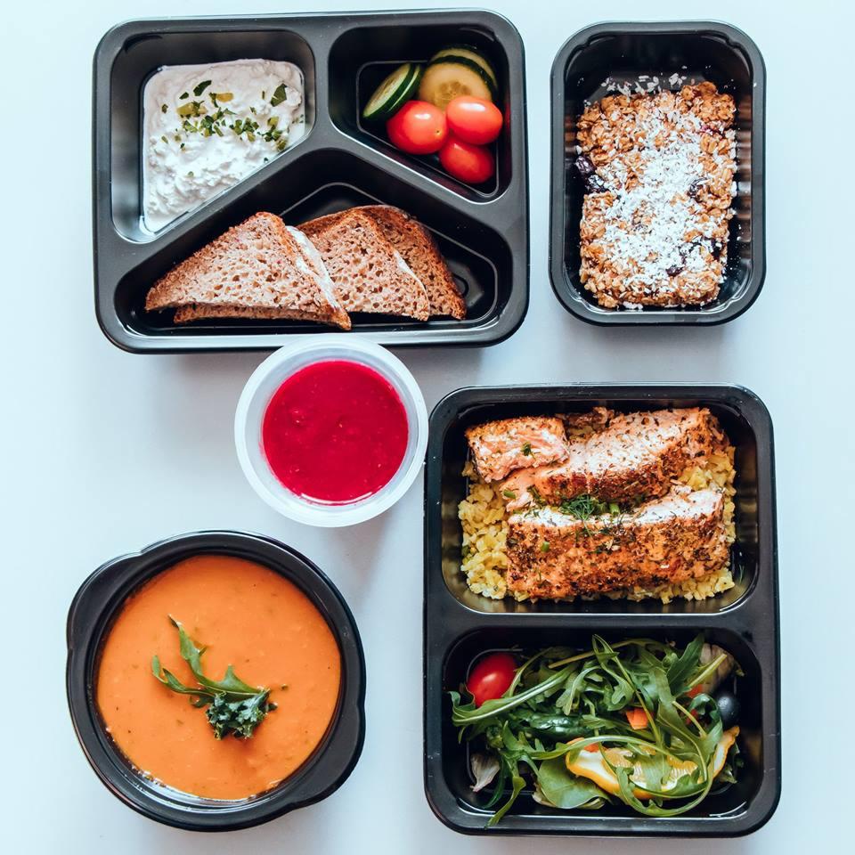 Zestaw pięciu pudełek z różnorodnymi daniami dietetycznymi, w tym zupa krem z zielonym akcentem, łosoś z kaszą, sałatka warzywna, pieczywo razowe z twarożkiem i warzywami oraz deser owsiany...