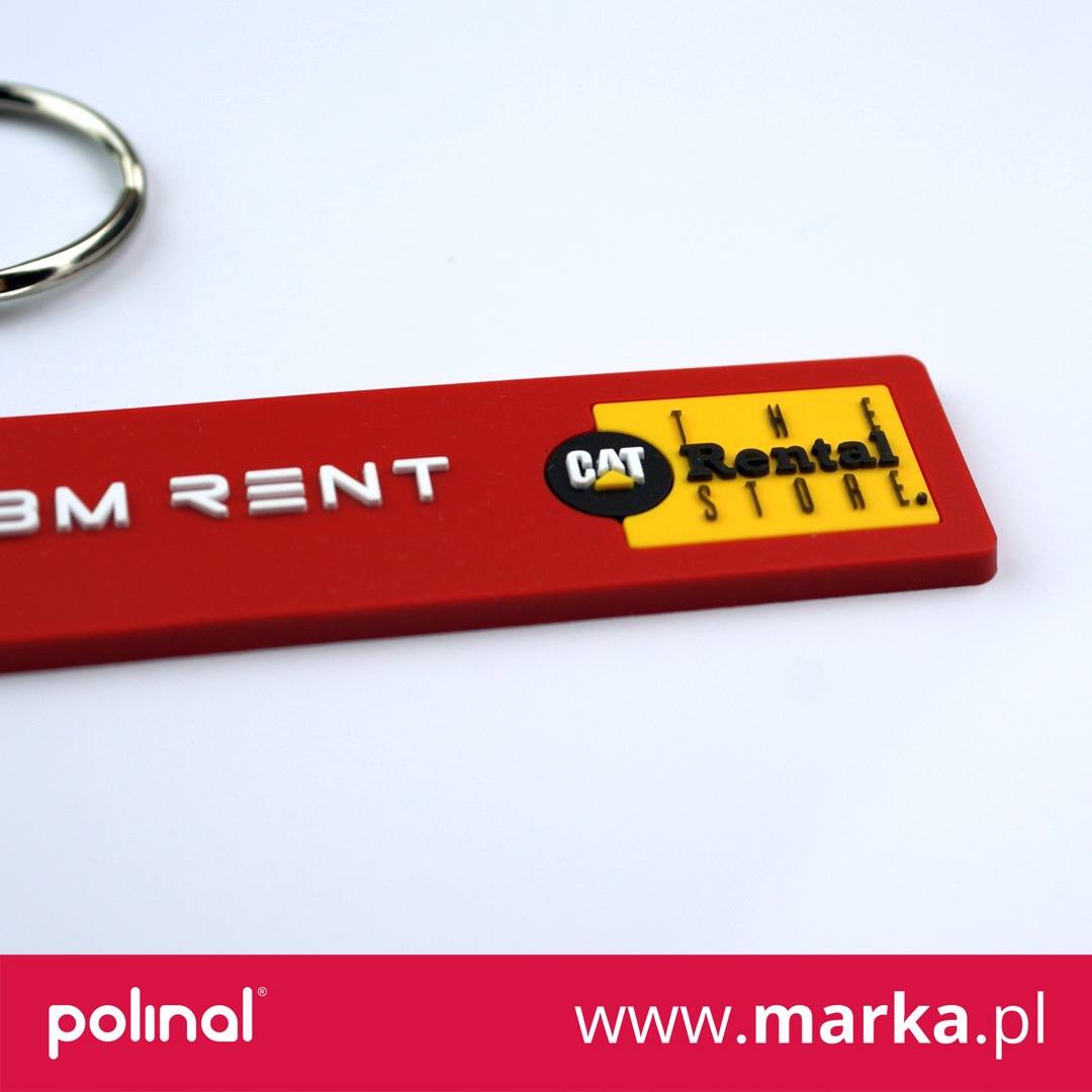 Czerwony brelok z logo CAT Rental Store i napisem BM RENT na białym tle, z metalowym kółkiem