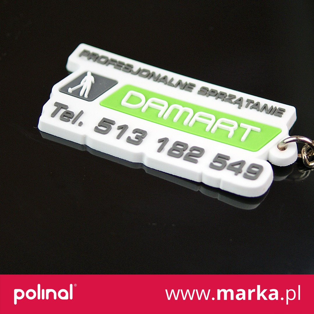 Biały brelok z logo firmy sprzątającej 'DAMART', z numerem telefonu i grafiką osoby grającej w golfa, na czarnym, błyszczącym tle.