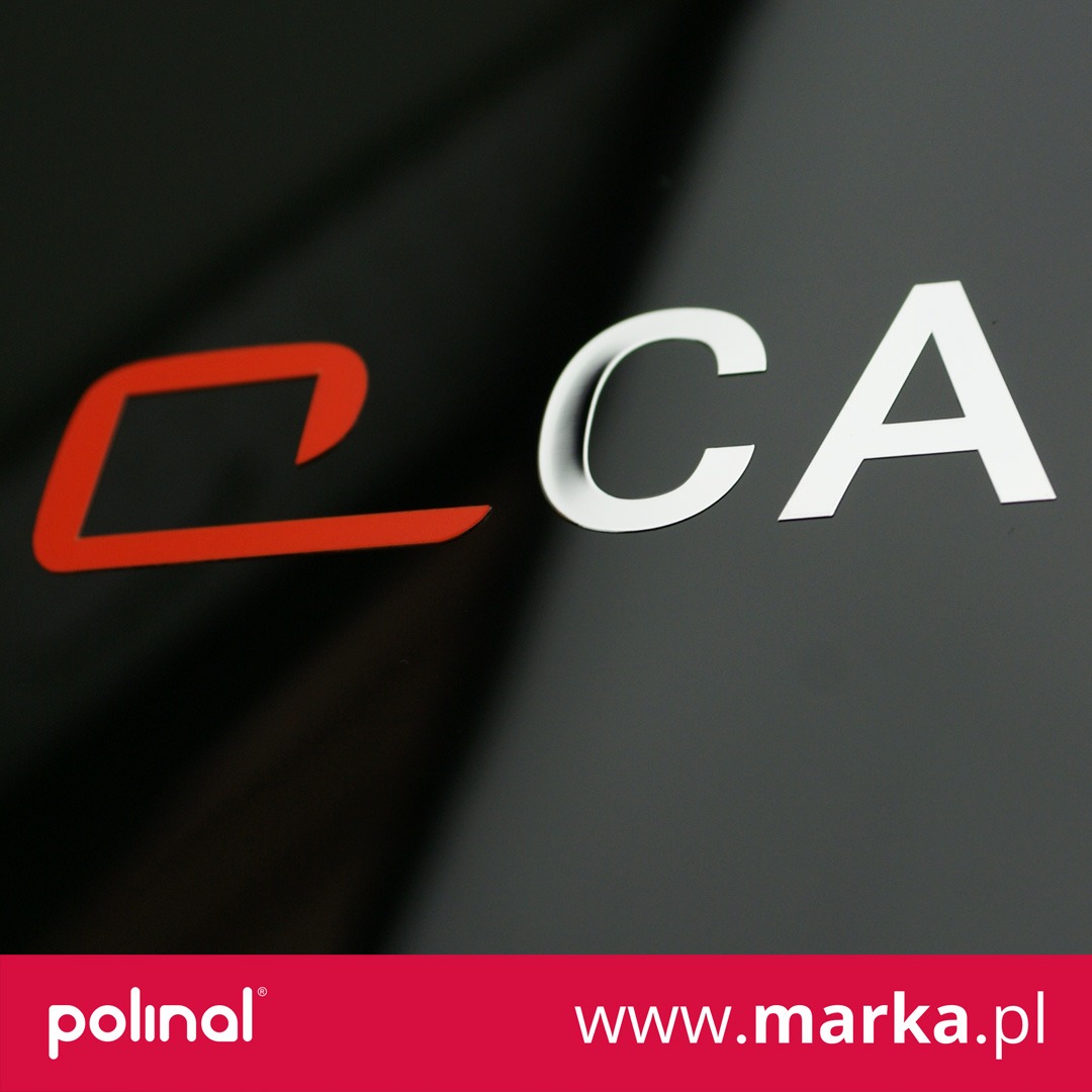 Czerwono-białe litery 'CA' na czarnym, błyszczącym tle, wykonane w technice druku płaskiego.