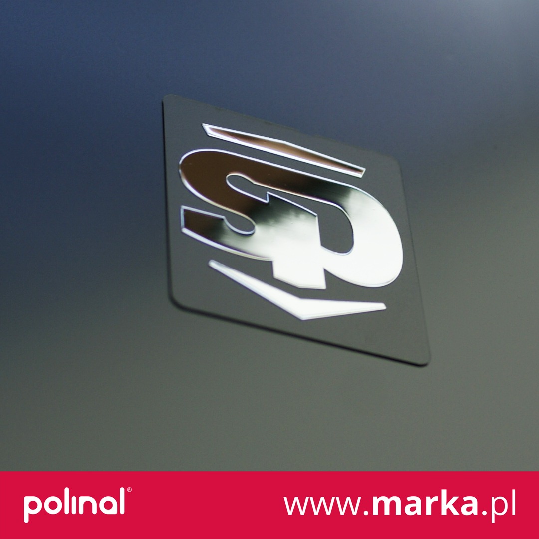 Błyszczące logo na czarnym tle, z efektem lustrzanego odbicia, widoczny fragment strony internetowej w dolnej części kadru.