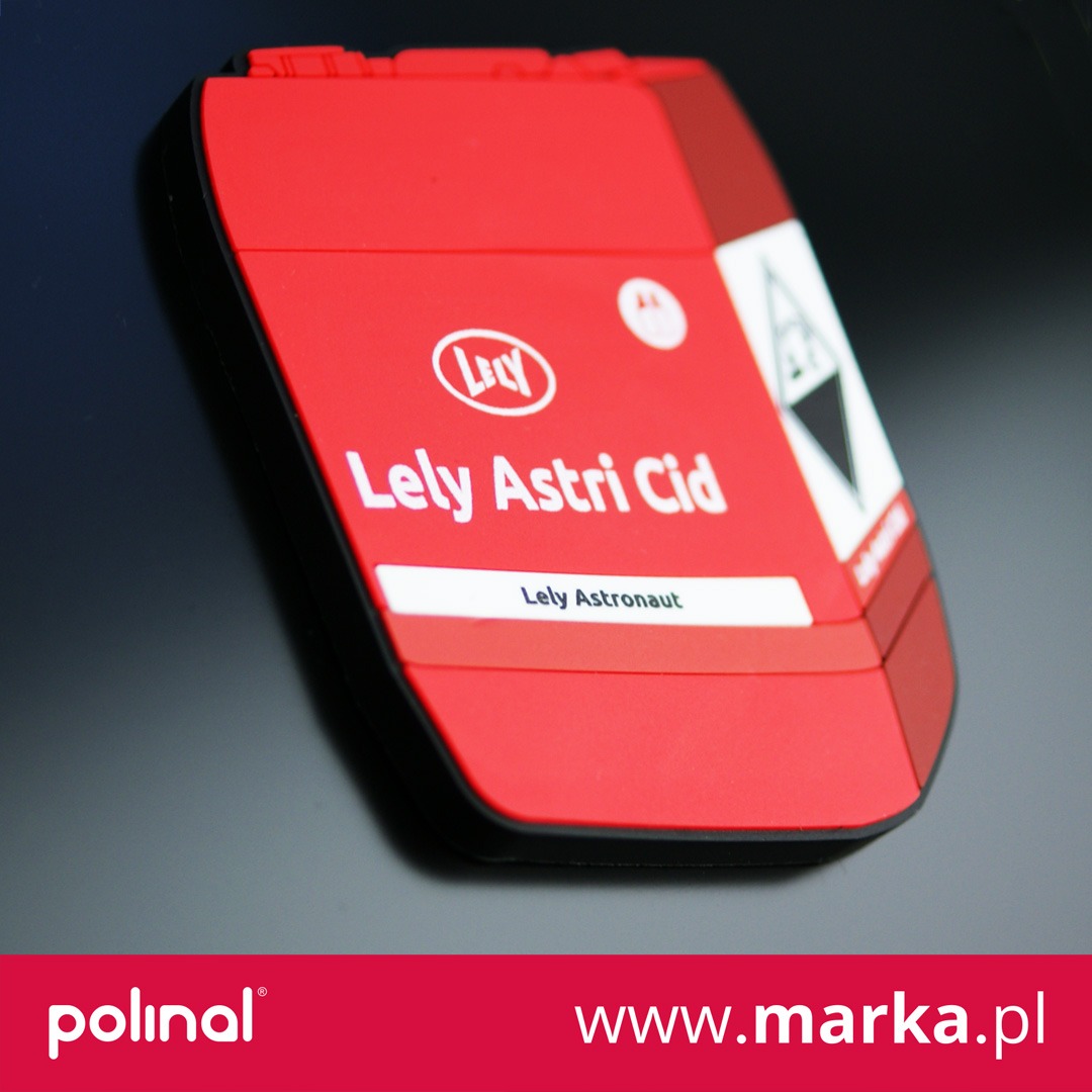 Czerwona, trójwymiarowa próbka produktu z nadrukowanym logo i nazwą Lely Astri Cid oraz Lely Astronaut, umieszczona na ciemnym tle.