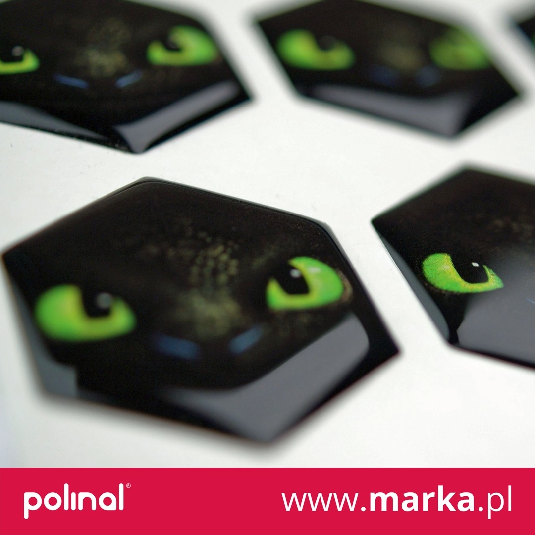 Sześciokątne, błyszczące naklejki z wizerunkiem smoka Szczerbatka na białym tle.