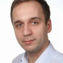 Portret mężczyzny w błękitnej koszuli na jasnym tle. Uśmiech, krótko ostrzyżone włosy. Zdjęcie biznesowe, profesjonalny wygląd.