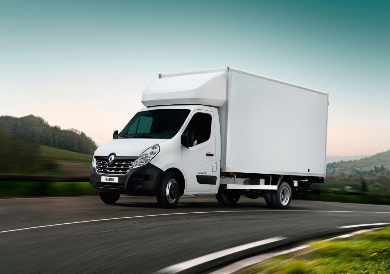 Biały samochód dostawczy Renault Master z zabudową kontenerową w ruchu na drodze w okolicach Bełchatowa. Widoczny z przodu, z lekkiego skosu.