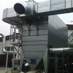 Duży, przemysłowy system wentylacji z metalowymi kanałami i drabinką, zainstalowany na zewnątrz budynku z widocznymi elementami konstrukcyjnymi.