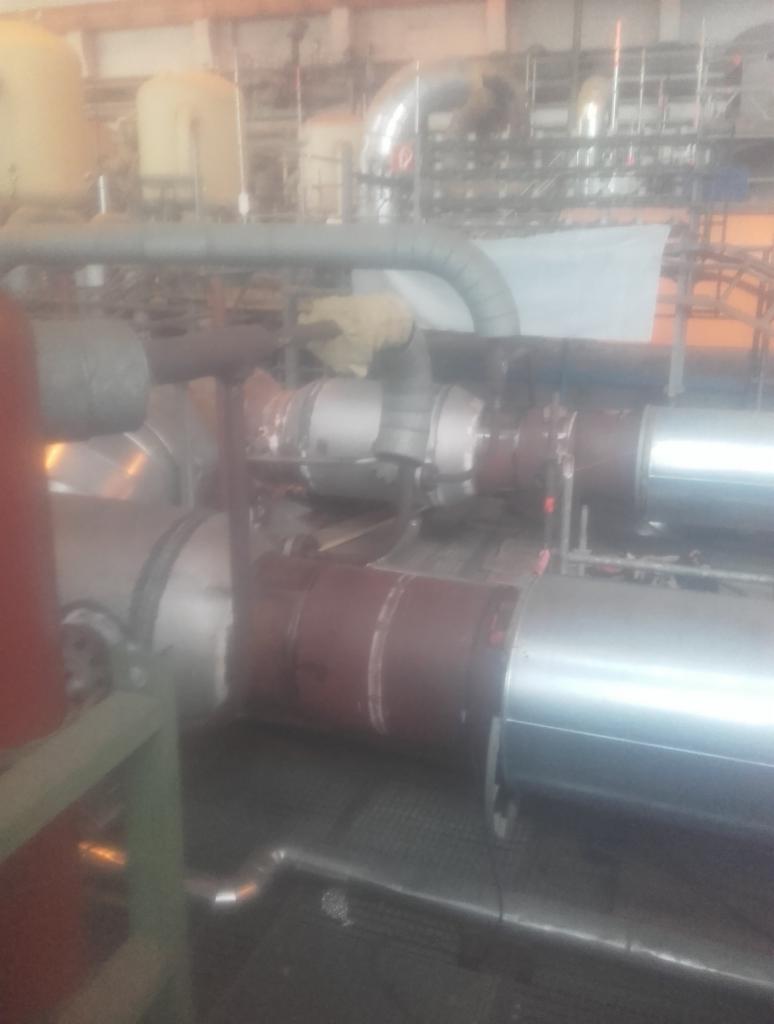 Instalacja przemysłowa z rurami i zbiornikami, widoczne spawane łączenia, w tle konstrukcja stalowa hali.