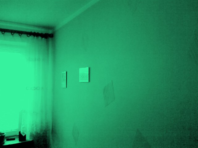 Zdjęcie przedstawia fragment pokoju po remoncie z elementami wykończenia, ściana pomalowana na zielono z drobnymi elementami dekoracyjnymi, okno z zasłonami w tle.