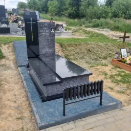 Nowoczesny nagrobek z ciemnego granitu Orion i Bengal Black z wysoką tablicą, prosta forma, otoczenie cmentarne.