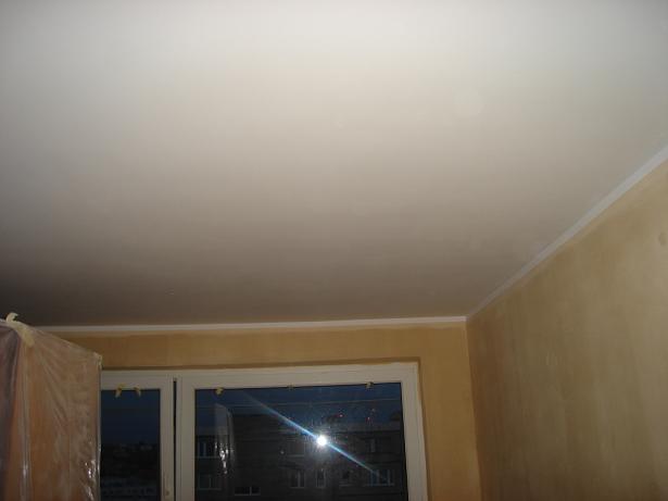 Pomalowane na biało wnętrze z widocznym oknem i sufitem z listwą wykończeniową, ściany w odcieniach beżu.