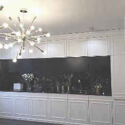 Marzena Camila Wojtkiewicz GREEN-ARTE pracownia wnętrz i malarstwa - Nowoczesna kuchnia z białymi szafkami w stylu klasycznym, czarnym blatem i marmurowym panelem. Nad blatem dekoracyjna lampa w stylu glamour.