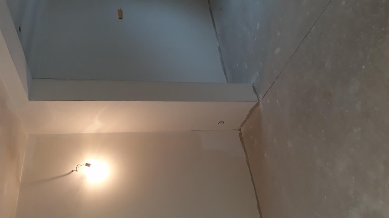 Surowe wnętrze w trakcie prac wykończeniowych, widoczne ściany po nałożeniu gładzi i surowa podłoga, przygotowane do dalszych prac.