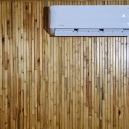 Biały klimatyzator marki Rotenso zamontowany na ścianie z drewnianych paneli, wyświetlający temperaturę 30 stopni Celsjusza.