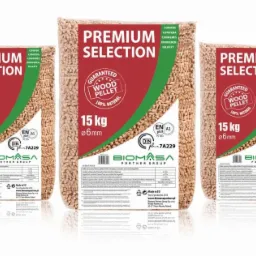 Trzy przezroczyste worki z pelletem drzewnym o średnicy 6mm i wadze 15kg, z etykietą 'Premium Selection' i logo Biomasa Partner Group, ustawione na białym tle.