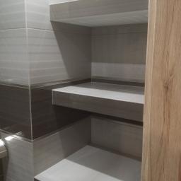OPALIŃSKI Nowoczesne Wykończenia - Półki z płytek w łazience, wykończone w odcieniach szarości, z widoczną strukturą drewna na framudze drzwi.