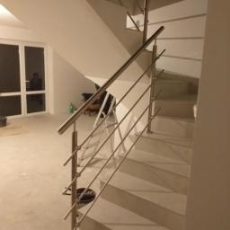 RÓŻYCKI GLASS Grzegorz Różycki - Nowoczesne schody z balustradą ze stali nierdzewnej, widok z dołu, w tle okno i drabina.