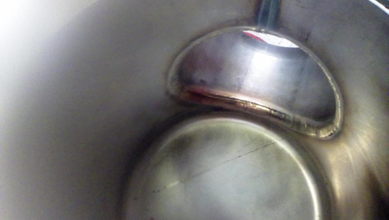 Wewnętrzne ujęcie spawu na metalowej konstrukcji, widoczne ślady obróbki i nierówności spoiny.