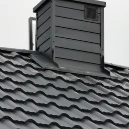 Szare dachówki ceramiczne z kominem wentylacyjnym w zbliżeniu, widoczne mocowania dachówek.
