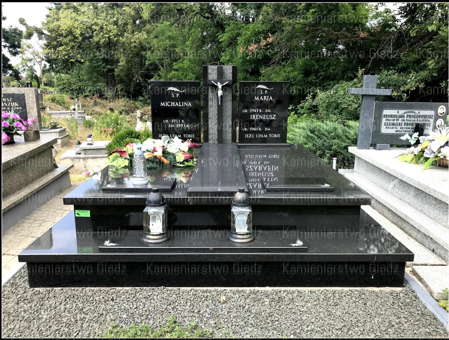 Podwójny, czarny pomnik z granitu na cmentarzu, z wygrawerowanymi imionami i datami, ozdobiony lampionami i kwiatami.