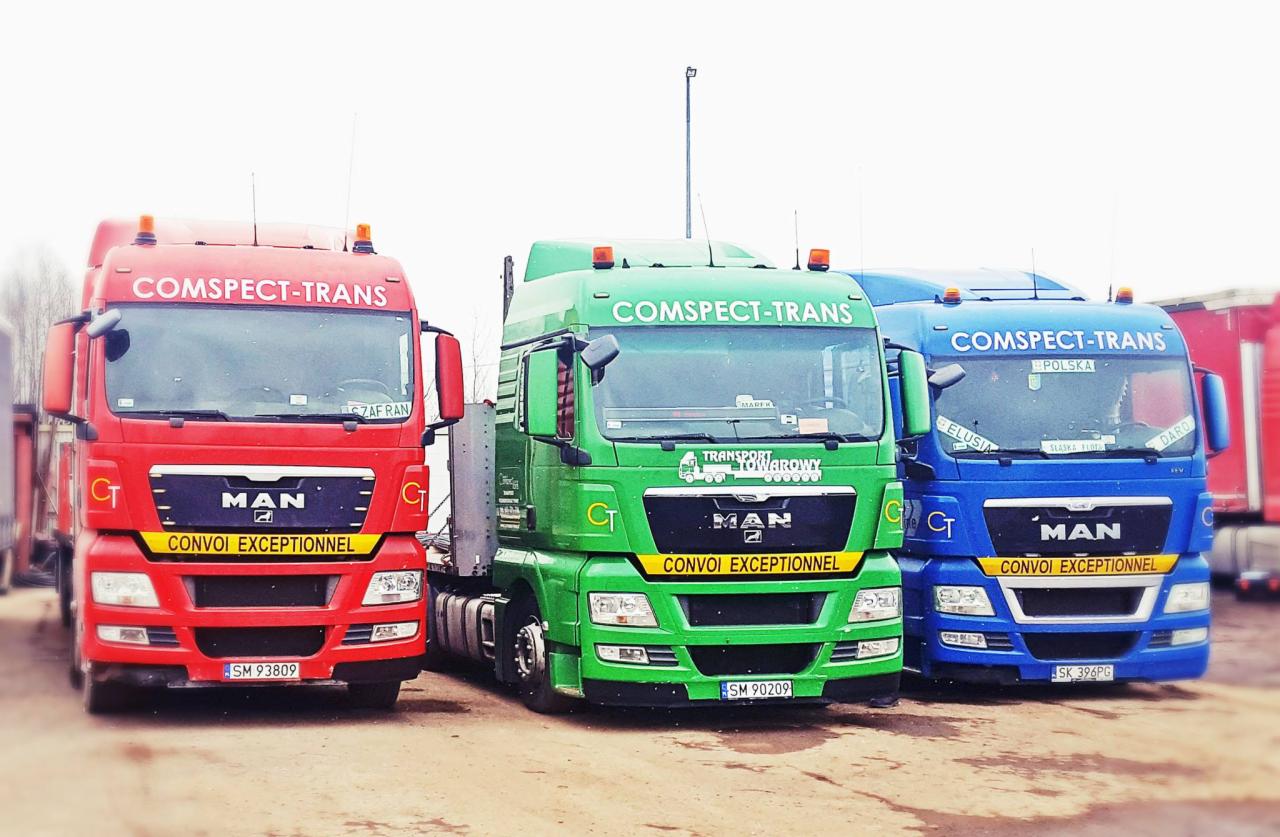 Trzy ciągniki siodłowe MAN w kolorach czerwonym, zielonym i niebieskim, należące do firmy COMPSPECT-TRANS, zaparkowane obok siebie na placu. Na każdym z nich widnieje napis 'CONVOI EXCEPTIONNEL'.