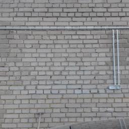 elektroabc - Szara ceglana ściana budynku z poprowadzonymi na zewnątrz rurami instalacji elektrycznej i puszkami przyłączeniowymi.