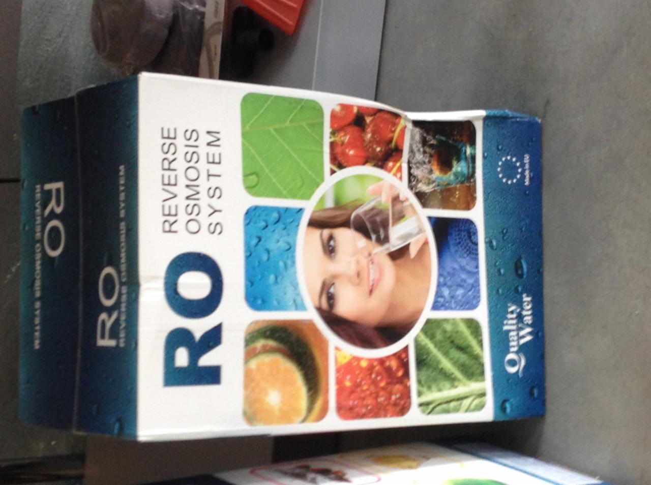 Pudełko systemu odwróconej osmozy RO z grafiką przedstawiającą czystą wodę i uśmiechniętą kobietę pijącą wodę ze szklanki.