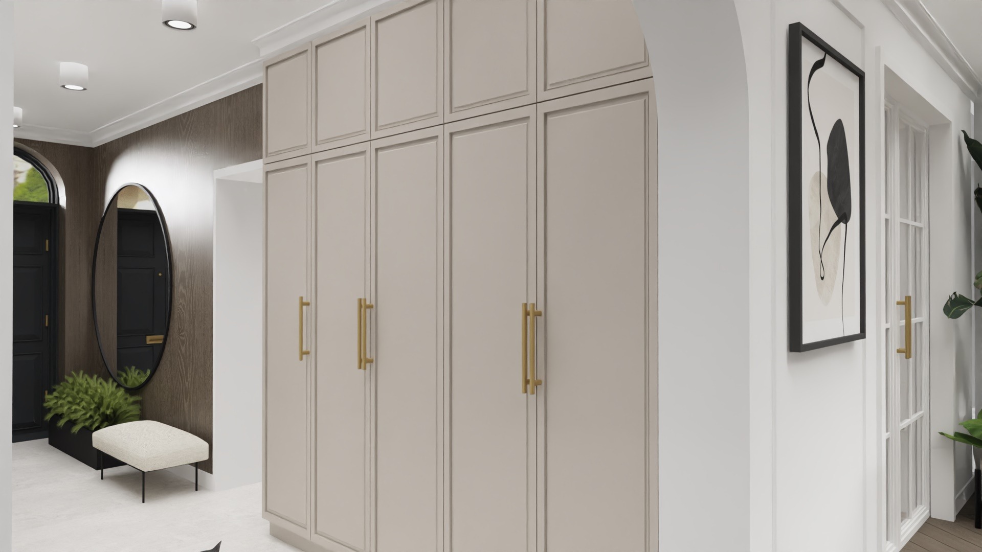 Hall z beżową zabudową szaf wnękowych z złotymi uchwytami, okrągłe lustro, minimalistyczny obraz w czarnej ramie i rośliny doniczkowe.