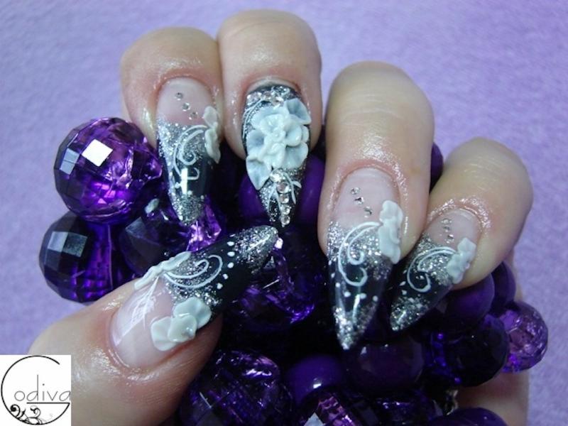 Stylizacja paznokci w Tychach: czarno-srebrny manicure z białymi kwiatami 3D na tle fioletowych kryształów.