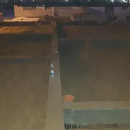 Wylany fundament pod budynek z wystającymi rurami kanalizacyjnymi; widoczna butelka wody i pomarańczowe rury w betonie.