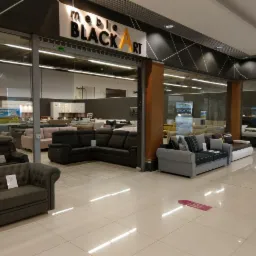 Wnętrze salonu meblowego z ekspozycją różnorodnych sof i narożników, w tle widoczne plakaty reklamowe marki 'meble BLACK ART'.