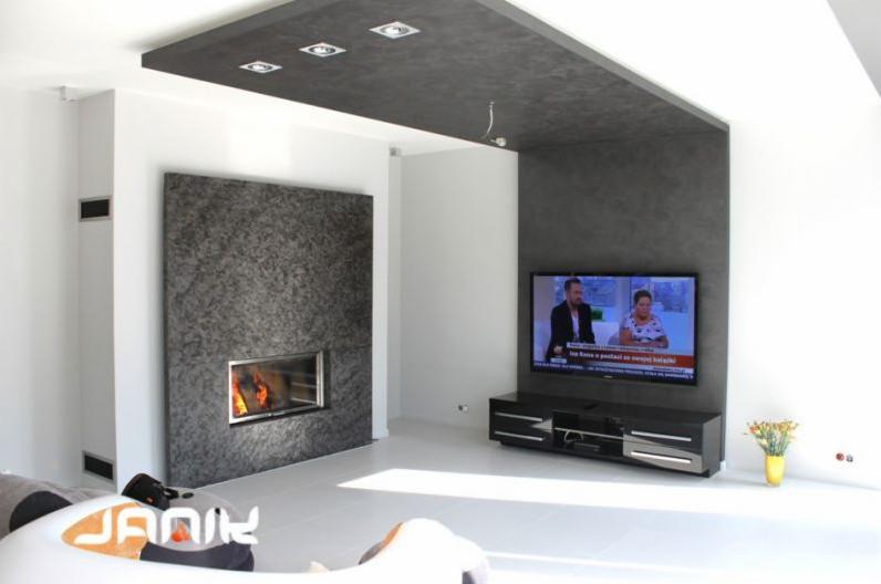 Nowoczesny salon z wbudowanym kominkiem obłożonym kamieniem dekoracyjnym, podwieszanym sufitem z oświetleniem punktowym i telewizorem LCD na ścianie.