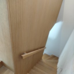 Usługi Stolarskie - Jasne, drewniane schody z barierką, widok z góry. Minimalistyczny design, naturalne wykończenie. Element wystroju wnętrza, nowoczesne schody.