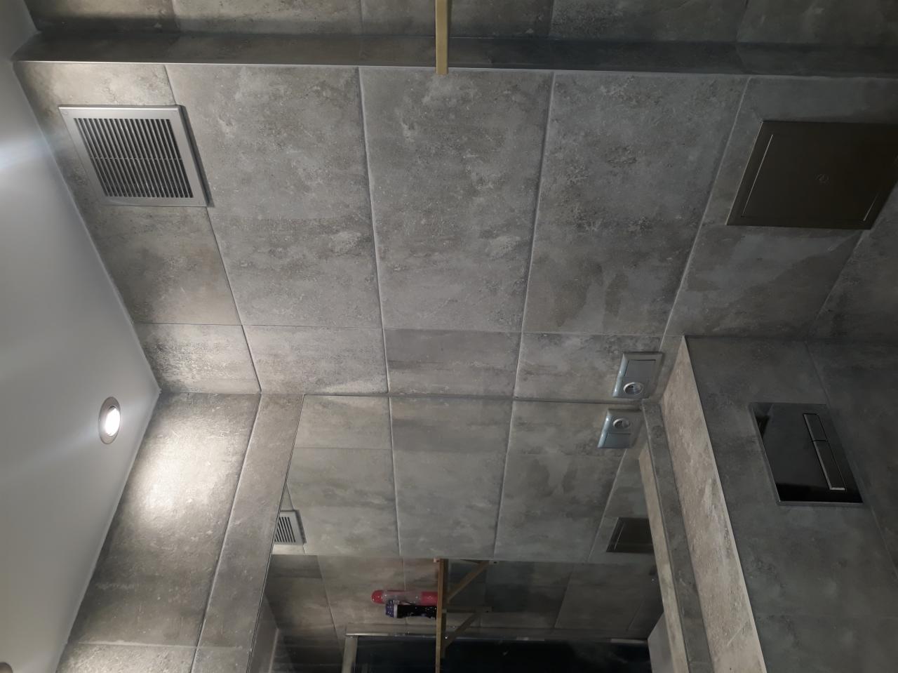 Wykończona łazienka w Łodzi z szarymi, matowymi płytkami na ścianach i suficie, widoczny wentylator sufitowy i zabudowa podtynkowa WC.