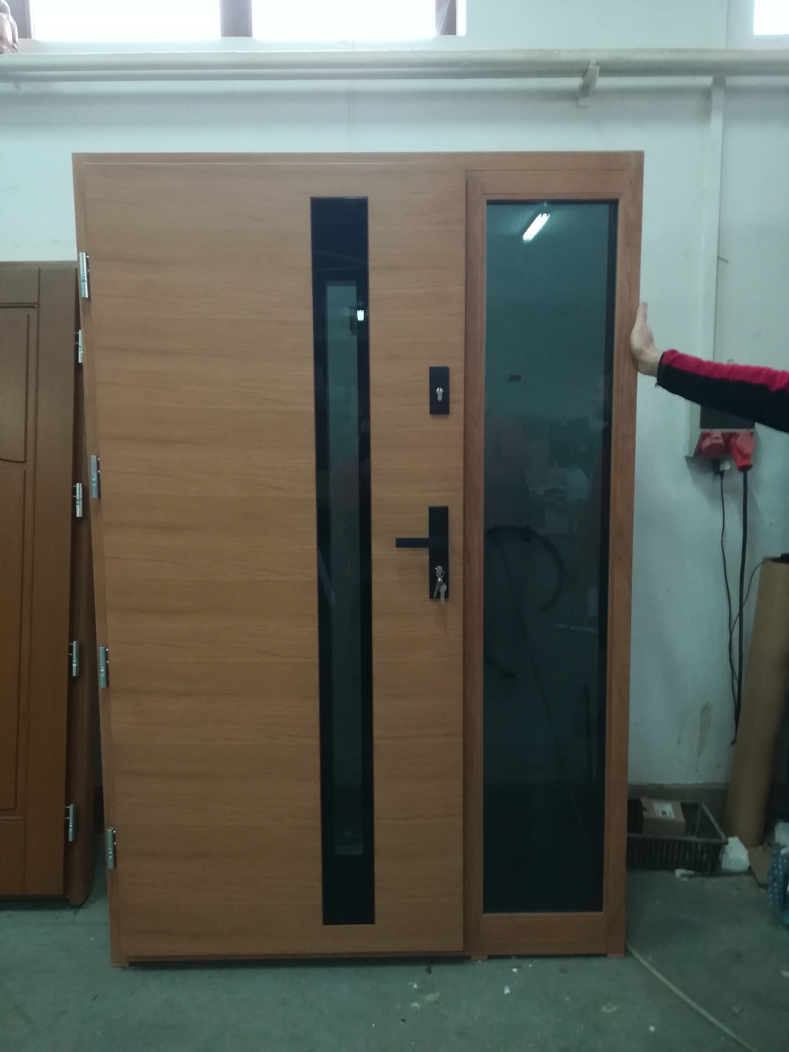 Komplet drzwi zewnętrznych z bocznym doświetleniem, w odcieniach brązu, z czarnymi akcentami. Widoczne detale zamka i klamki. Ujęcie w warsztacie.