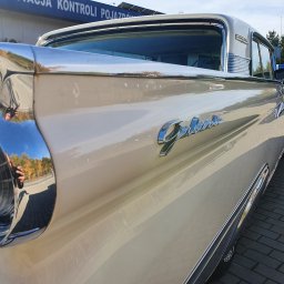 Mobilna Myjnia Parowa Steam Power Łukasz Salwin - Fragment odrestaurowanego, kremowego Forda Galaxie z 1959 roku w Dąbrowie Chełmińskiej, z widocznym chromowanym reflektorem i napisem 'Galaxie', stojącego na kostce brukowej.