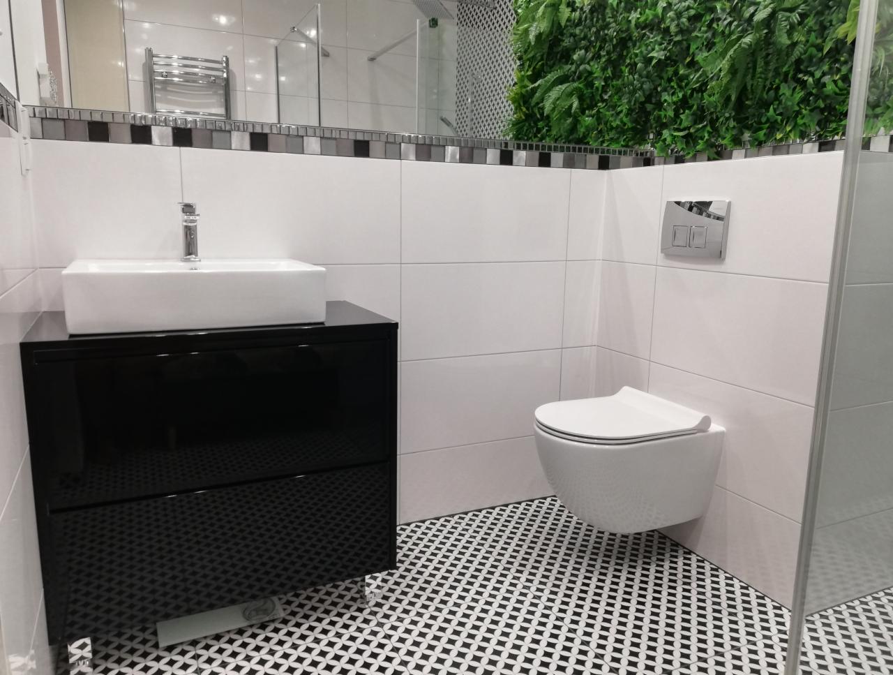 Nowoczesna łazienka z białą armaturą, czarną szafką pod umywalką i mozaikową podłogą w czarno-białe wzory, akcentem zieleni w postaci pionowego ogrodu na ścianie.