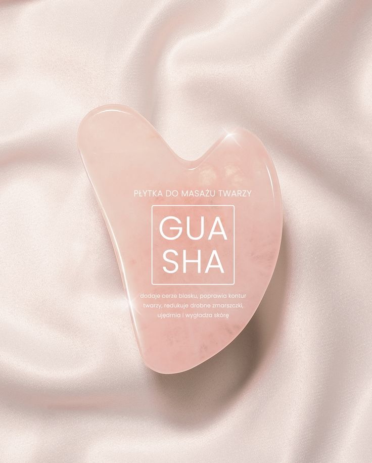 Różowa płytka Gua Sha do masażu twarzy na satynowym tle. Produkt do pielęgnacji skóry, poprawiający kontur i redukujący zmarszczki. Zdjęcie produktowe w delikatnej tonacji.