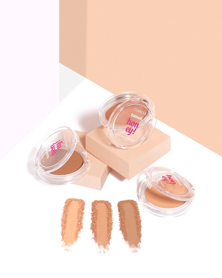 Claresa Tanned Honey bronzer: trzy odcienie pudru w przezroczystych opakowaniach, rozsypane obok próbki kolorów na białym tle, ułożone na beżowym podeście.