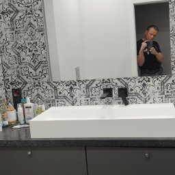 fliesen-tech - Nowoczesna łazienka z umywalką nablatową i wzorzystymi płytkami. W lustrze odbija się osoba robiąca zdjęcie.